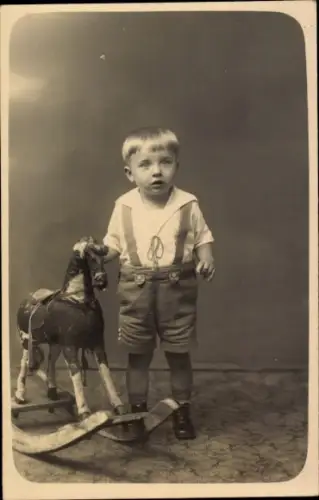 Foto Ak Kind neben einem Schaukelpferd, Spielzeug