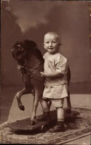 Foto Ak Kind neben einem Schaukelpferd, Spielzeug
