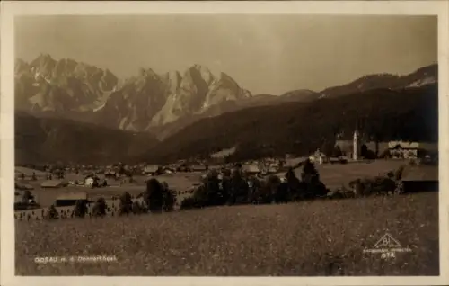 Ak Gosau in Oberösterreich, markante Berggipfel, Wiese im Vordergrund, verstreute Häuser, Kirche 