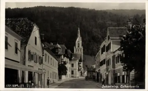 Ak Schladming Steiermark, Straße mit Kirchturm, Häuserreihen beidseits, Bergwald im Hintergrund, 