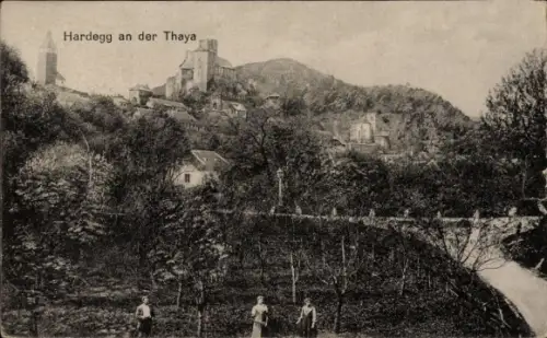 Ak Hardegg in Niederösterreich, Hügel mit markantem Turm, Fluss mit Brücke rechts, dichtes Gehölz
