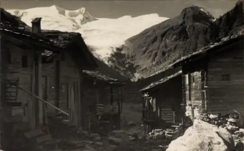 Ak Prägraten am Großvenediger in Tirol, Holzhütten, schmaler Weg zwischen Häusern, Gletscher im H