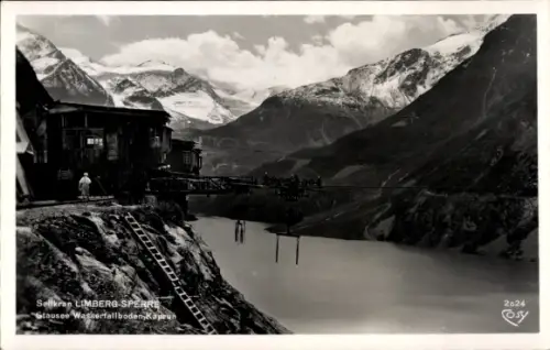 Ak Kaprun in Salzburg, Stausee mit Berggletscher-Hintergrund, Holzgebäude am Fels, Steg über Wass