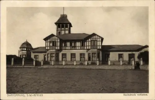 Ak Swakopmund Namibia, Zweigeschossiges Haus mit Turm, Kuppel links, Zaun, sandige Fläche, Text '