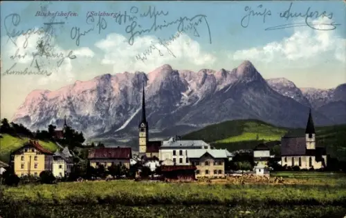 Ak Bischofshofen in Salzburg, Kirchturm, zweiter Turm, Häuserreihe, grüne Wiese, markante Bergket