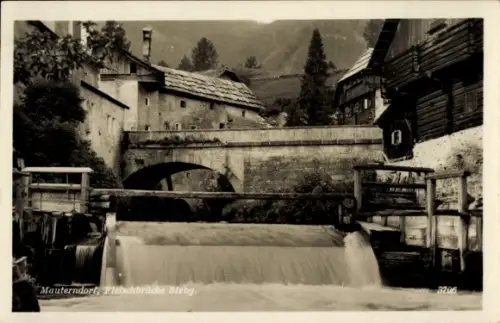 Ak Mauterndorf in Salzburg, Steinbrücke, Wehr mit fallendem Wasser, Holzhäuser beidseitig, Bäume 
