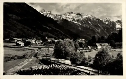Ak Kleinarl in Salzburg, gestapelte Baumstämme, Landstraße, Bäume, Dorf mit Kirchturm, Tal mit sc