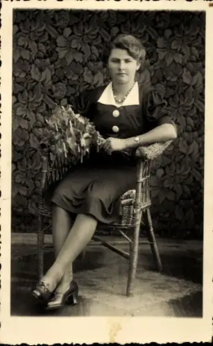 Foto Ak Frau mit Blumenstrauß, Sitzportrait auf einem Korbstuhl