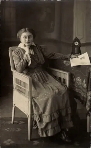 Foto Ak Frau in einem Korbstuhl sitzend, Portrait mit Zeitung