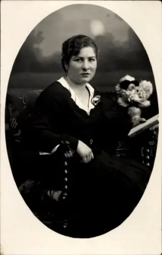 Foto Ak Sitzportrait einer jungen Frau, Buch in der Hand, Blumenvase