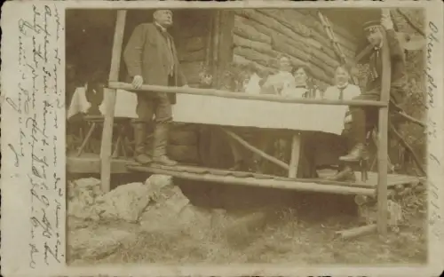 Foto Ak Oberrieden Kanton Zürich, Gruppe am Tisch vor einer Holzhütte, Student