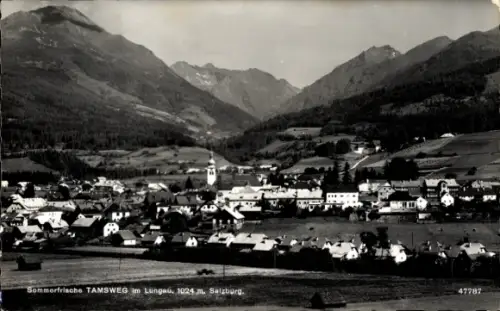 Ak Tamsweg in Salzburg, Dorf im Tal, Kirche mit Turm, viele Häuser, Wiesen im Vordergrund, Berge 