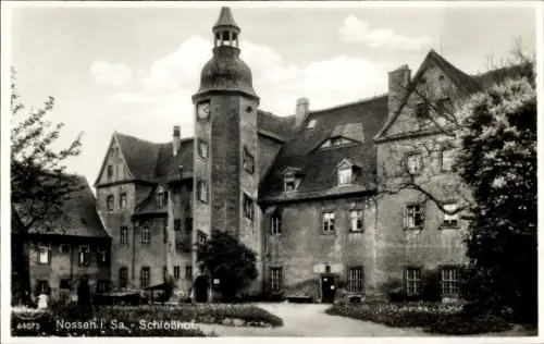 Ak Nossen in Sachsen, mehrstöckiges Gebäude mit rundem Turm und Uhr, viele Fenster, Weg und Bepfl