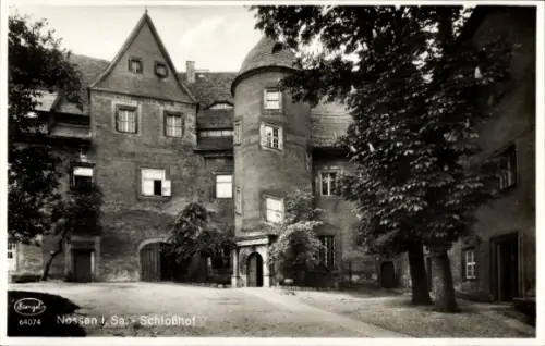 Ak Nossen in Sachsen, Runder Turm, Torbogen mit Eingang, mehrstöckige Fassade mit Fenstern, Bäume