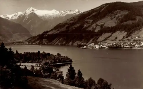 Ak Zell am See in Salzburg, See mit Ufer und Bäumen, Halbinsel im Vordergrund, schneebedeckte Ber