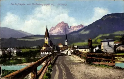 Ak Bischofshofen in Salzburg, Holzbrücke, Fluss, Weg mit Schatten, zwei Kirchtürme, Berggipfel im