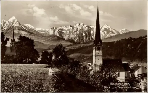 Ak Bischofshofen in Salzburg, Kirche mit hohem spitzem Turm, Bergkette im Hintergrund, Feld und F