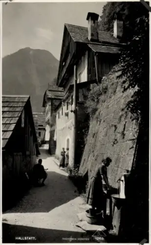 Ak Hallstatt Oberösterreich, Häusergasse, Brunnen, Frau mit Eimer