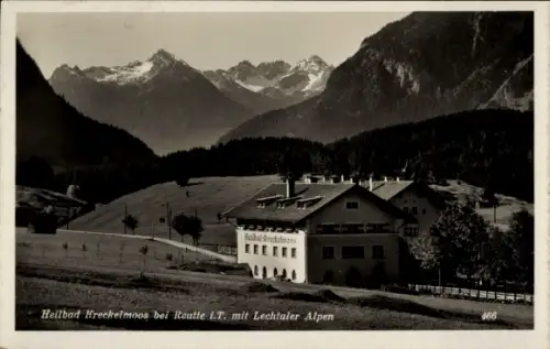 Ak Reutte in Tirol, Heilbad-Gebäude, Wiesen, Zaun, Nadelwald, schneebedeckte Berggipfel