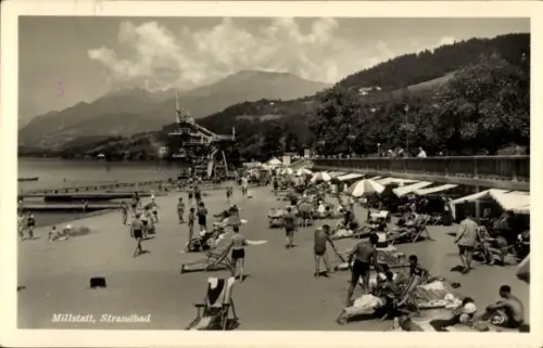 Ak Millstatt am See Kärnten, Strandbad  viele Badegäste, Sonnenschirme, Berge im Hintergrund