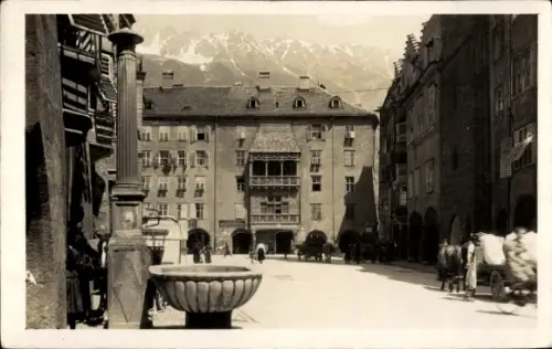 Ak Innsbruck in Tirol, Goldener Erker mit Balkon, Brunnen vorn, Menschen und Pferdewagen, Berge i