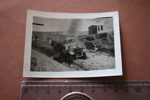 altes Foto ausgebranntes Fahrzeug , dahinter deutsche Panzer