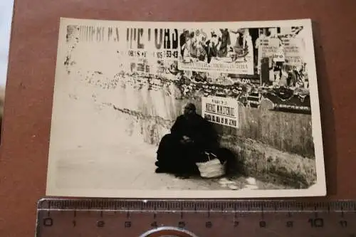 Altes Foto - alte Frau sitzt an Mauer mit Plakaten - Spanien ??