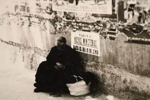 altes Foto - alte Frau sitzt an Mauer mit Plakaten - Spanien ??