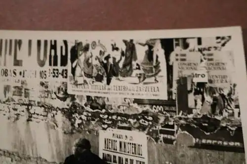 altes Foto - alte Frau sitzt an Mauer mit Plakaten - Spanien ??