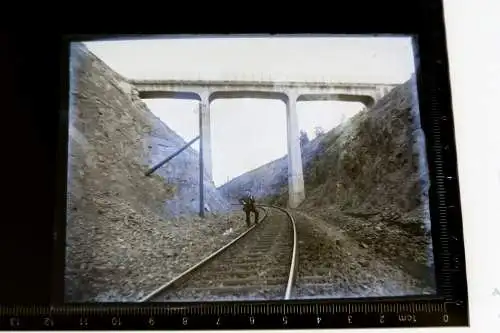 altes Glasnegativ - Mann auf  Bahnstrecke, darüber eine Brücke 