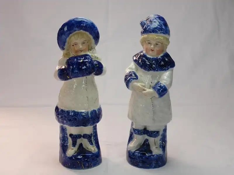 Paar Porzellanfiguren, um 1900, ungemarkt, Mädchen und Junge in Wintersachen, blau-weiß bemalt, im Fuß des Mädchens Brandrisse, sonst unbeschädigt. H: 22 cm 0