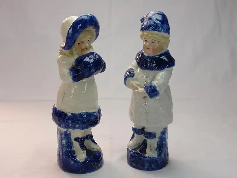 Paar Porzellanfiguren, um 1900, ungemarkt, Mädchen und Junge in Wintersachen, blau-weiß bemalt, im Fuß des Mädchens Brandrisse, sonst unbeschädigt. H: 22 cm 4
