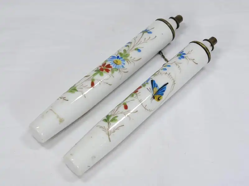 Zwei Porzellankerzen, Ende 19. Jh., wohl Frankreich, mit Blumenranken und Schmetterlingen bemalt, mit Petroleum befllbar, ein Haarri. H: 19 cm 0
