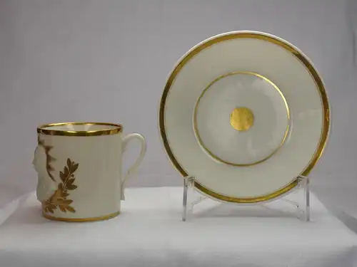 Tasse und Untertasse, deutsch, um 1815-20, ungemarkt, im Stil von Sevres, zylindrische Form, verziert mit Halbportraits von Wellington und Blücher in Biskuitporzellan vor einer goldenen Sonne, umrandet von goldenen Lorbeerzweigen, bezeichnet "La...