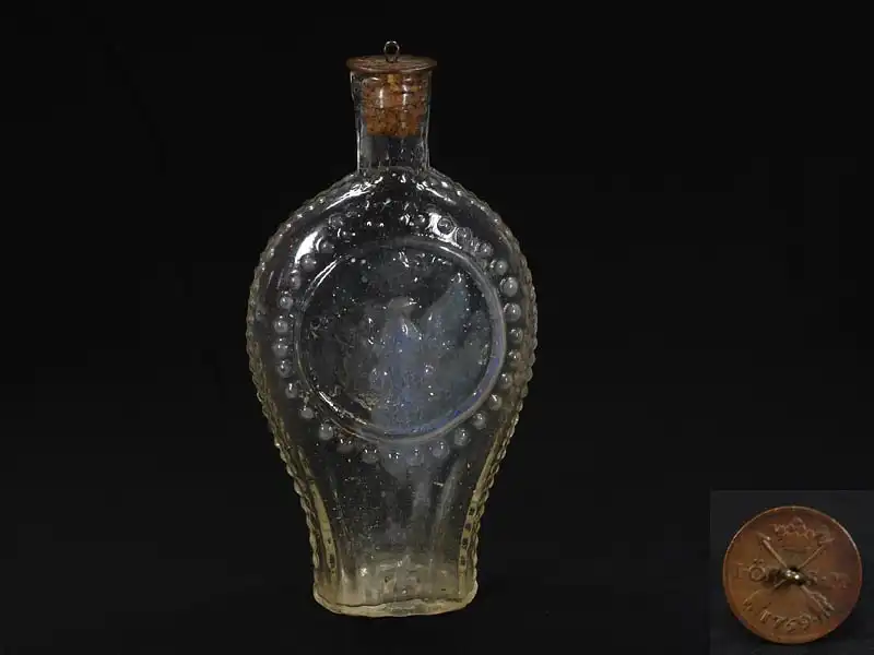 Schnapsflasche, 2. Hälfte 19. Jh., formgeblasen, verziert mit Abbild eines halbplastischen Portraits eines Mannes in Uniform und rückseitig eines halbplastischen Adlers mit Krone, alter Korkstöpsel, montiert mit einer schwedischen Münze von 1759,... 0