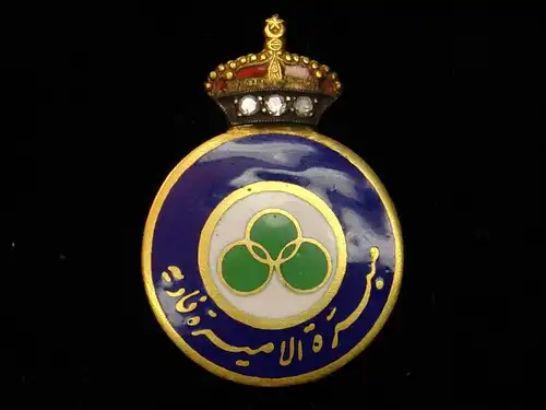 Geschenkbrosche des Königreiches von Saudi Arabien, runde Goldbrosche, blau emailierter Kranz mit arabischer Inschrift, weiß emaillierter Innenkreis mit drei ineinander verschlungenen grünen Kreisen, aufgesetzte Goldkrone, rotemailliertes Futter,...
