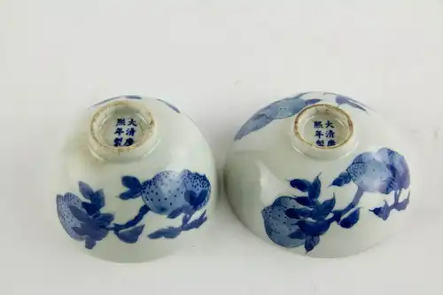 2 Schälchen, China, 19. Jh., gemarkt, Kangxi, verziert mit Glückspfirsichen in feiner Blaumalerei, alte Risse und Krakel, sonst unbeschädigt.
