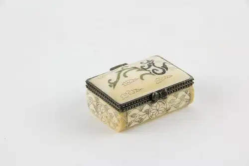 Kleine Dose,
Tibet, 20. Jh., Bein, Deckel mit Ornamenten verziert, Korpus graviert und geschwärzt, Gebrauchsspuren. 
L: 4,5 cm, B: 3 cm
Little box with cover, bone, Tibet, 20th century, decorated, good condition