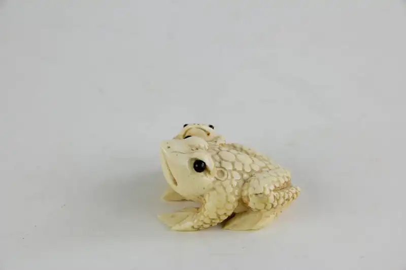 Netsuke,

Japan, Edo Meijij, Elfenbein, signiert, Kröte mit Jungtier, geschnitzt, dunkel eingelegte Augen, Gebrauchsspuren.

H: 2,5 cm 1
