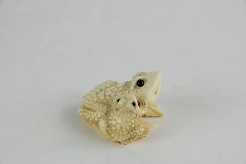 Netsuke,

Japan, Edo Meijij, Elfenbein, signiert, Kröte mit Jungtier, geschnitzt, dunkel eingelegte Augen, Gebrauchsspuren.

H: 2,5 cm 2