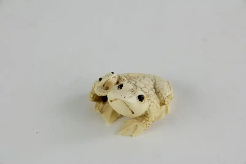 Netsuke,

Japan, Edo Meijij, Elfenbein, signiert, Kröte mit Jungtier, geschnitzt, dunkel eingelegte Augen, Gebrauchsspuren.

H: 2,5 cm 4