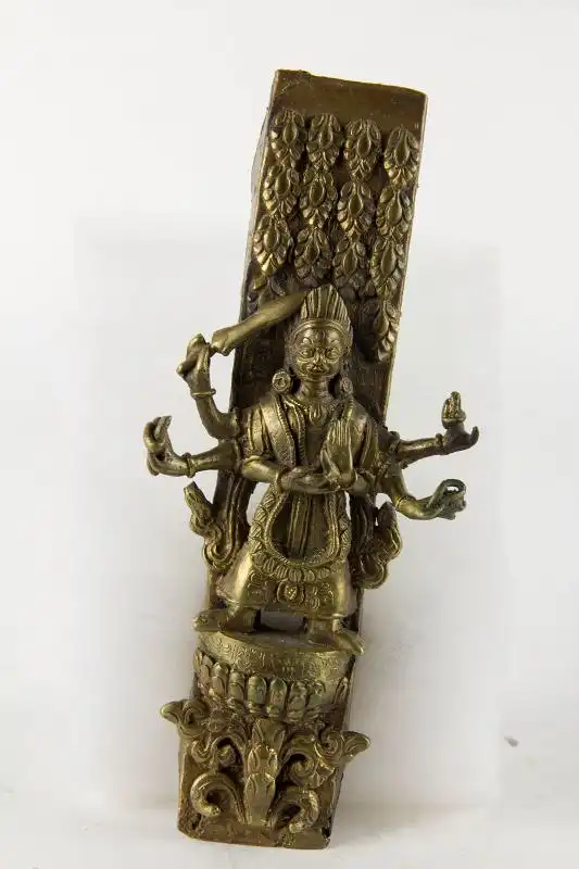 Beschlag, wohl Nepal. 20. Jh., Bronze, mehrarmige Götterfigur (Durga), geschnitten und graviert, auf Lotussockel, mit Inschrift. 
L: 18 cm, B: 7,5 cm 0