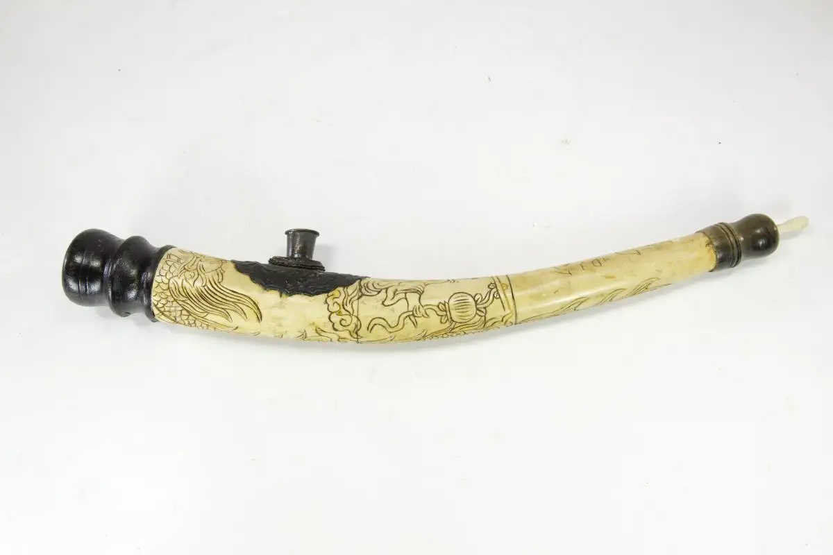 Opiumpfeife, China, 19./20. Jh., Bein, Horn, Holz und Kupfer, gebogenes Beinmittelstück, verziert mit Drachen und Schriftzeichen, als Abschluss gedrechselte Holzteile, Gebrauchsspuren, guter Zustand. L: 40 cm 0