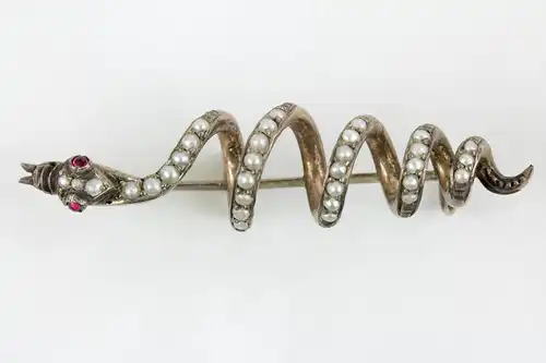 Brosche,
19. Jh., Silber, nicht gestempelt, in Form einer Schlange, mit Flussperlen und zwei Rubinen besetzt, sehr dekorativ, Gebrauchsspuren. L: 4,5 cm
