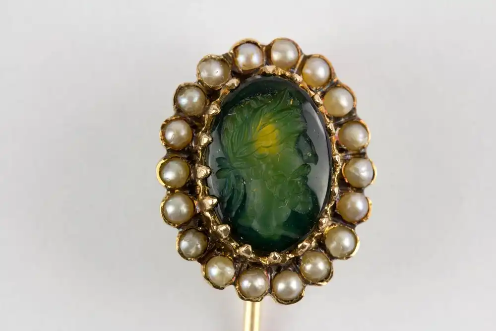 Krawattennadel, Niederlande, um 1870, Eichenblatt-Punze für 585er Gold, mittig grüner Stein mit geschnittenen antiken Portrait, von kleinen Flussperlen flankiert, sehr schöne Juwelierarbeit. L: 7 cm. 0