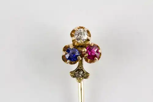 Krawattennadel, um 1900, 585er Gold, ungemarkt, in Form eines Kleeblattes, mit Saphier, Diamant und Rubin besetzt, im Stil kleiner Rosendiamant. L: 5,5 cm.