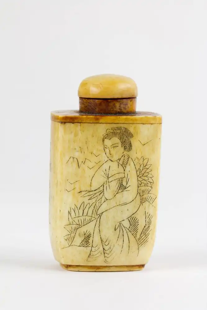 Schnupftabak-Dose, um 1900, wohl China, Bein, umlaufend verziert mit geschwrzten, gravierten Darstellungen einer Frau und Schriftzeichen. H: 6 cm. 0