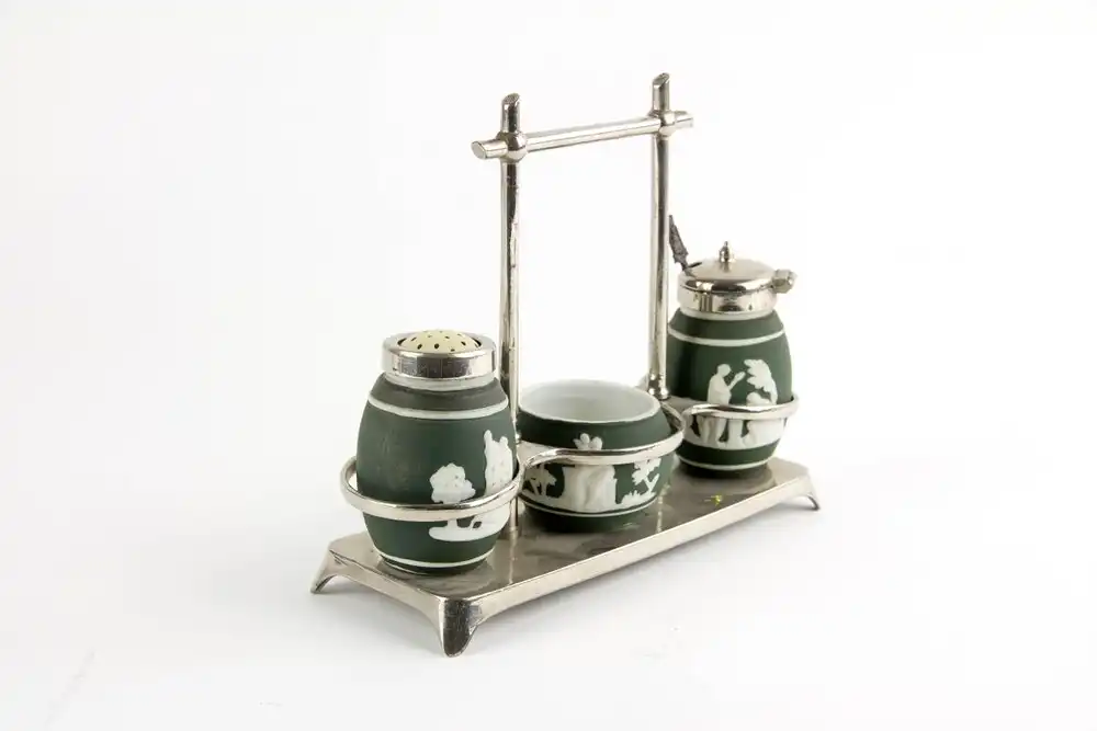 Menage, um 1900, im Stil von Wedgwood, vernickeltes Gestell mit Silberlöffel, sehr originell, Gebrauchsspuren. B: 6,5 cm, H: 15 cm, L: 18 cm. 1