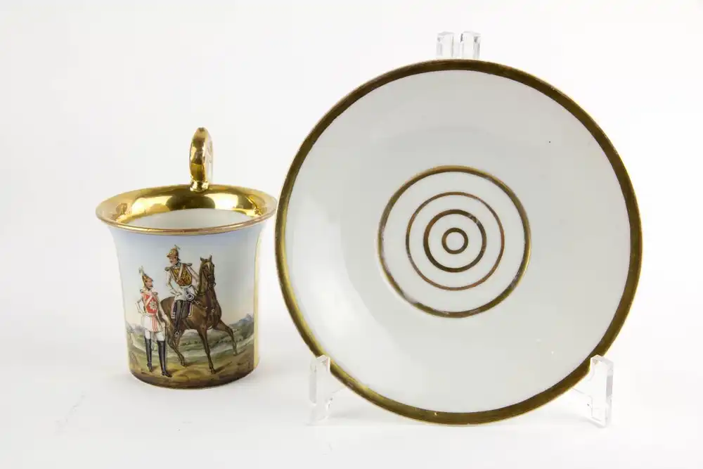 Tasse und Untertasse, Mitte 19. Jh., Berlin oder Schlesien, mit Pseudo- Zepter Marke, auf Schauseite Darstellung eines Offiziers der Garde de Corps in Supraweste auf Pferd, daneben ein Offizier der Garde Kürassiere in Parade, sehr feine Malerei,... 2