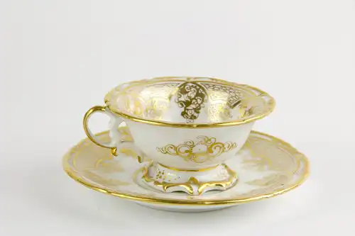 Tasse und Untertasse, Schlesien, Mitte 19. Jh., Gold- und Blumenmalerei, auf Tassengrund Darstellung eines pfeiferauchenden Puttos auf Wolke. H: 6 cm.